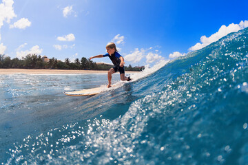 Happy surf boy - young surfer learn to ride on surfboard with fun on sea waves. Active family lifestyle, kids outdoor water sport lessons, swimming activity in surfing camp. Summer vacation with child