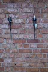 Close up view of two black iron candle holders on brick wall background. Exterior concept.