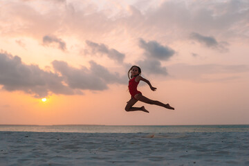 Adorable happy little girl on white beach at sunset.