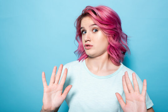 young woman with pink hair showing no gesture on blue background