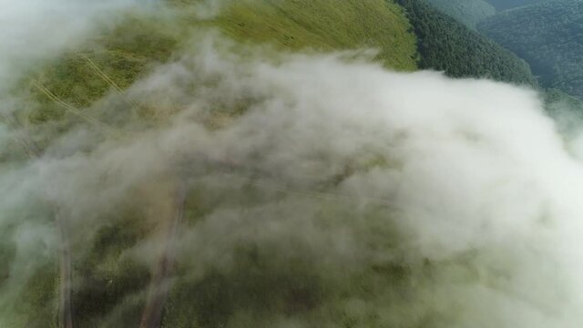 Departure from the fog over Mount Gemba. Flight over the summer mountains. Ukrainian Carpathian Mountains.