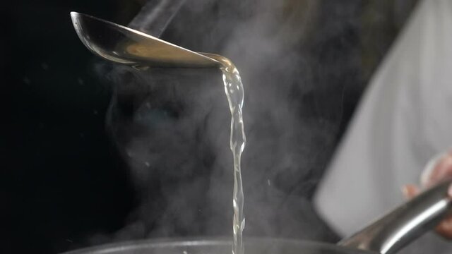 Chef cooking in restaurant. slow motion food video. Cooking delicious seafood risotto in frying pan. Fish broth being poured out of ladle. Traditional Italian cuisine. Full hd