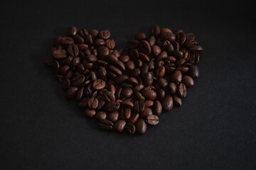 fresh roasted coffee beans on the black background in heart shape