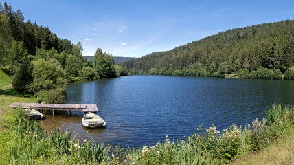 Idyllischer See mit Boot am Holzsteg, aufgenommen an der Nagoldtalsperre im Schwarzwald, Deutschland