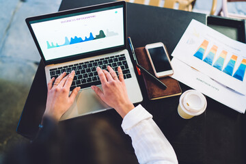 Crop faceless female using laptop in cafe