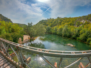 Landscape view of river Cetina from old metal bridge. Group of tourist preparing for a rafting adventure. Blato on Cetina, Autumn in Croatia.