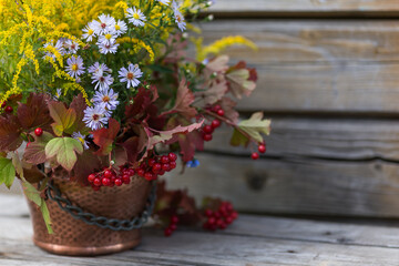 Autumn bouquet of flowers with viburnum berries in a copper planter outdoors