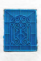 Tunisian blue window with decorative grate in white wall. Typical house in the medina of Hammamet town, Tunis. House details in North Africa