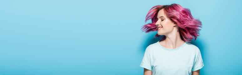 young woman waving pink hair on blue background, panoramic shot