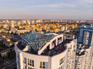 Group of adults peoples doing yoga outdoors on the roof of the High Building. Outdoor group yoga classes back view. Many people do yoga exercises. Meditation and wellness lifestyle concept in Kyiv