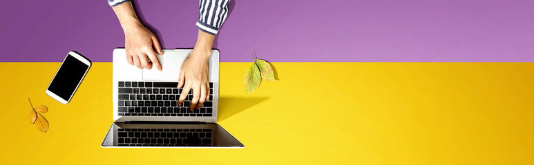 Autumn leaves with person using a laptop computer from above