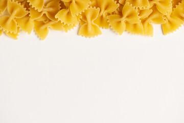 Farfalle - one of types of traditional Italian pasta. Border of macaroni products  on a white background,  for advertising, blogging, cooking recipes, packaging with copy space