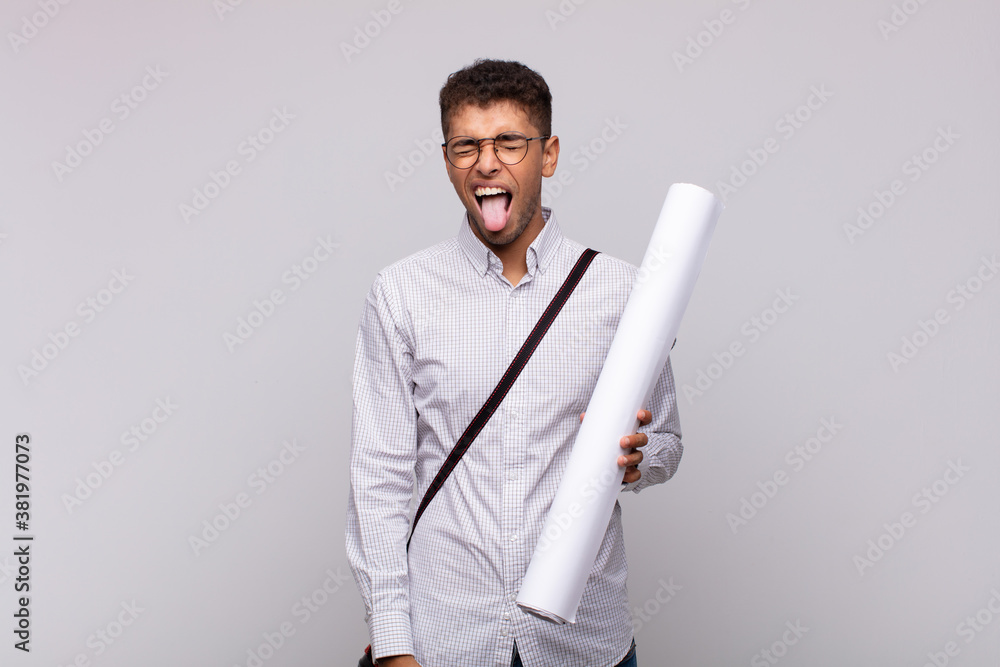 Wall mural young architect man with cheerful, carefree, rebellious attitude, joking and sticking tongue out, ha