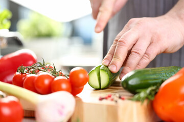 Male Hands Cutting Green Organic Cucumber Photo. Assorted Ripe Vegetables. Small Cherry Tomato on Wooden Board. Delicious Dieting Ingredient. Man Cooking Food at Kitchen Horizontal Photography