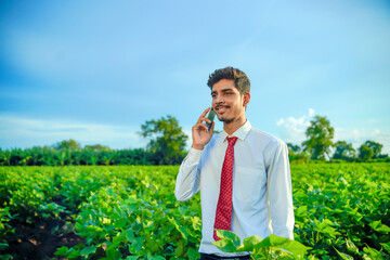 young indian handsome agronomist talking on smartphone at field