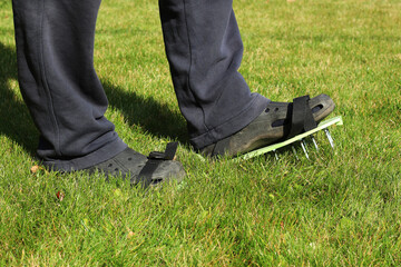 Aeration of the lawn with sandals. Garden concept