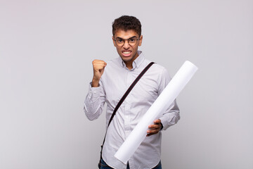 young architect man shouting aggressively with an angry expression or with fists clenched...