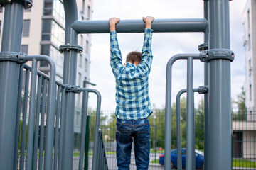 a boy in a hat and a checkered shirt, sitting on the Playground