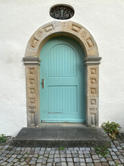 Historische türkise Tür eingerahmt in Rundbogen aus Sandstein
