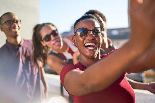 Happy playful young friends taking selfie on sunny patio