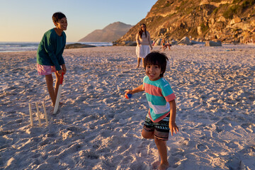 Portrait happy family playing cricket on sunny beach