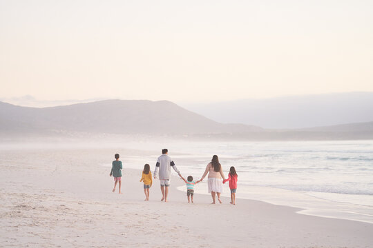 Family holding hands walking on ocean beach, Cape Town, South Africa