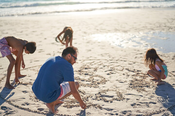 Family drawing in sand on sunny beach