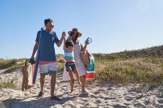 Playful family walking in sand on sunny beach path