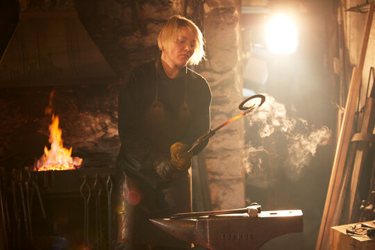 Female blacksmith working in sunny workshop