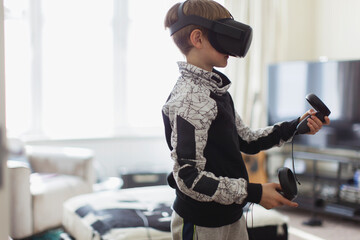 Boy playing video game with VRS goggles in living room