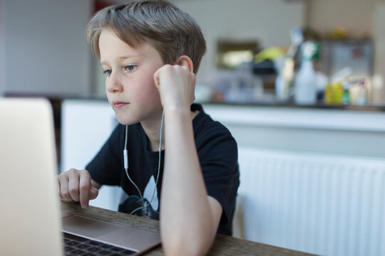 Focused boy with headphones homeschooling at laptop