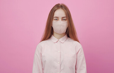 Portrait of young female wearing face mask looking at camera isolated on pink background