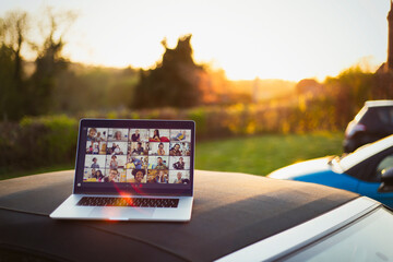 Friends video chatting on laptop screen on top of car