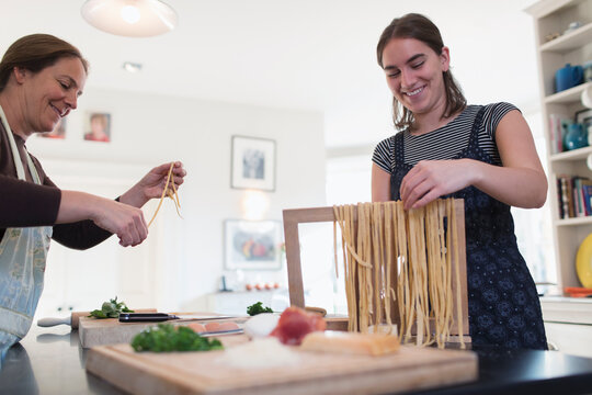 Mother And Daughter Making Fresh Homemade Pasta In Kitchen