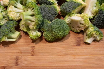 cut pieces of broccoli on an old wooden chopping board with empty space for slogan