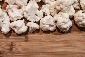 cut pieces of cauliflower on an old wooden chopping board with empty space for slogan