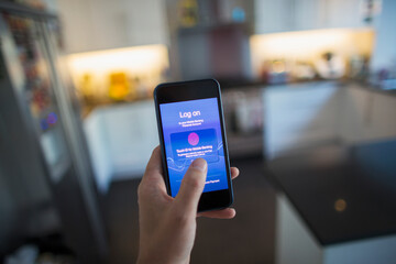 POV Man using touch ID on smart phone in kitchen