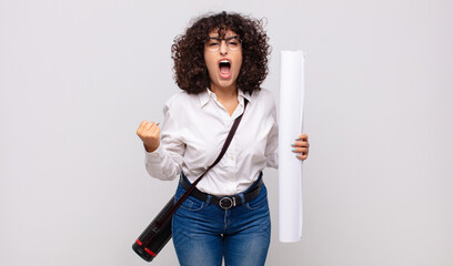 young architect woman shouting aggressively with an angry expression or with fists clenched...