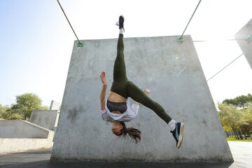 Girl jumps upside down on a parkour playground