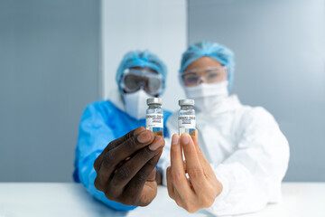 Close up on Vaccine. Multiethnic scientists in laboratory holding vial of coronavirus vaccine. The...