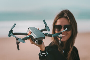 Cute modern lady pilot holds drone in her hand. Outdoors hobby. Focus on the drone.