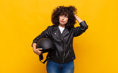motorbike rider woman feeling puzzled and confused, scratching head and looking to the side