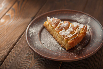 A piece of homemade pie on a plate of powdered sugar in a rustic style. Sliced apple pie with icing close-up and copy space.