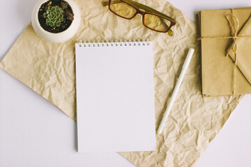 A notebook, a pen and glasses for vision lie on the desktop.