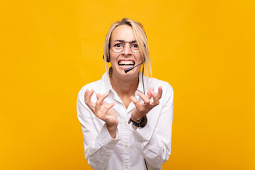 young woman telemarketer looking desperate and frustrated, stressed, unhappy and annoyed, shouting...