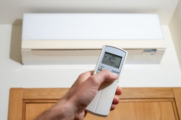 View of a hand turning on the air conditioning by the remote control