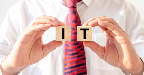 information technologies concept. IT acronym text on wooden cube blocks in hands of businessman