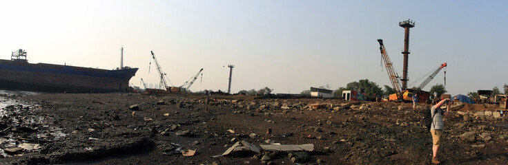 Shipbreaking Yard in Darukhana, Mumbai, India &ndash; INS Vikrant dismantling with scrap metal & workers in background