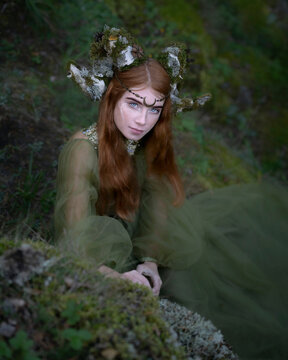 Young red-haired woman with horns on her head  between the stones