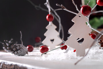 White wooden Christmas decoration with red beads, cones and lights